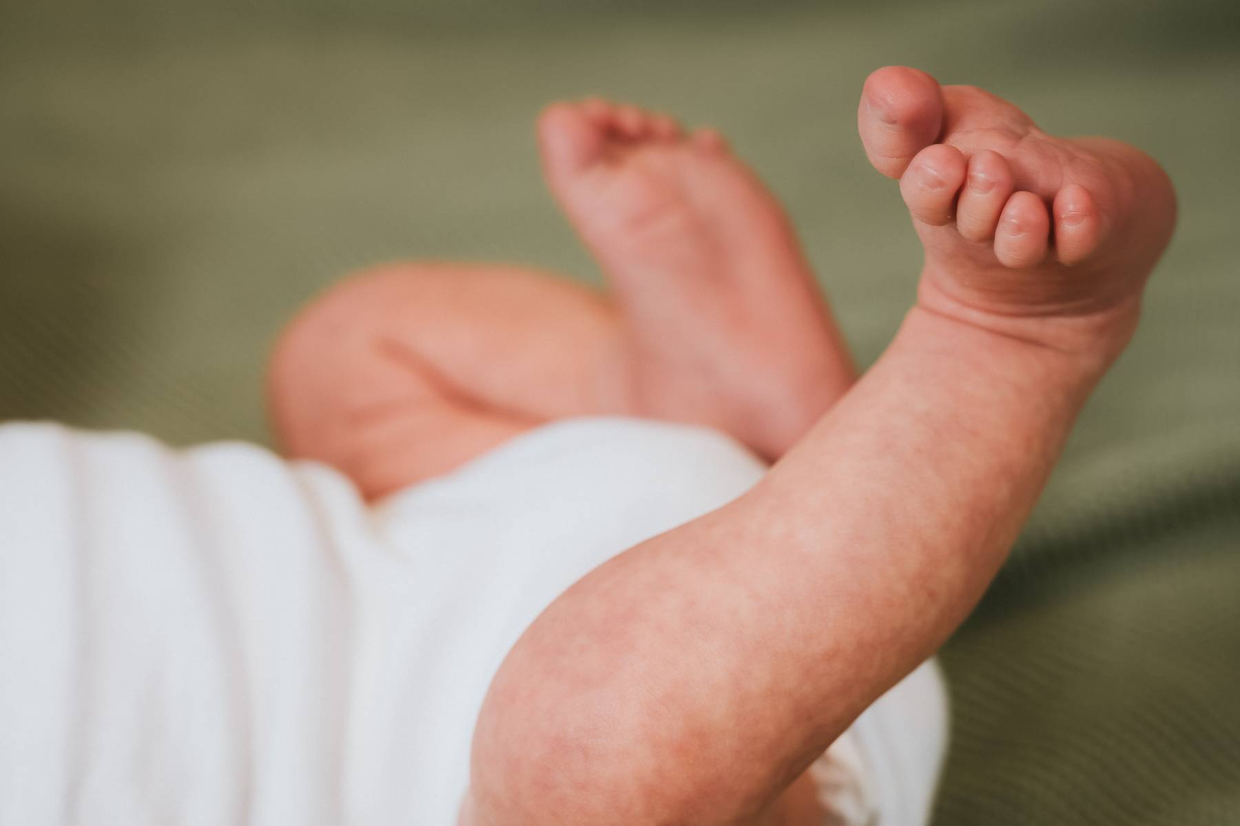 Newborn photography detail shot of crocheted baby outfit and personalized green blanket for new kids, Salt Lake City