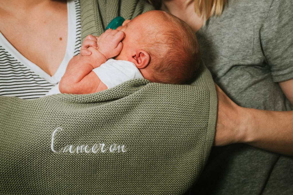 Utah newborn photographer capturing lifestyle newborn session for two moms in Millcreek home