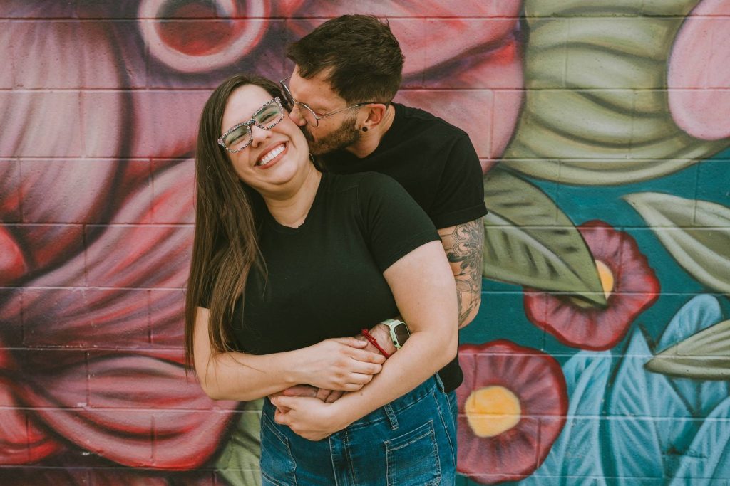 Couple posing in front of large floral street art mural during Salt Lake City family session