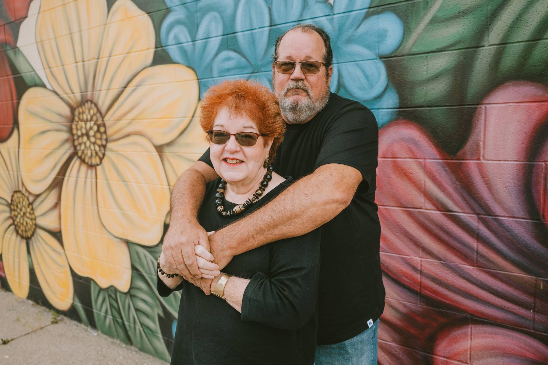 Family photos at Salt Lake City mural with bold floral backdrop and coordinated black outfit style