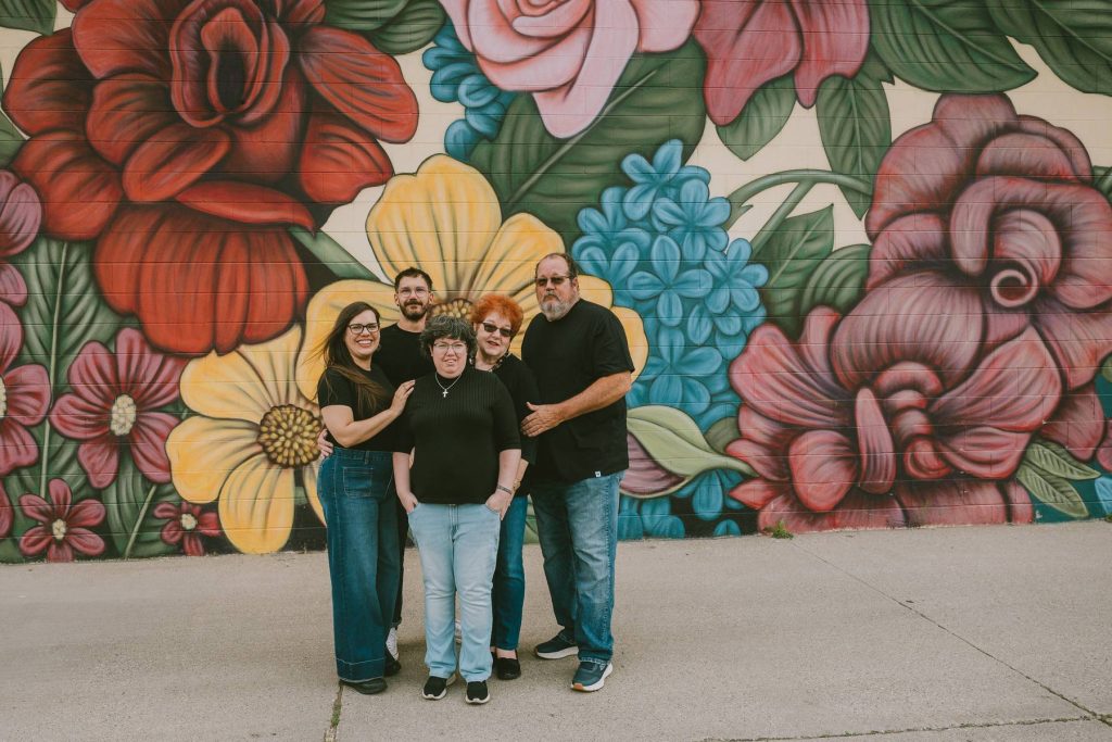 Utah family photographer capturing extended family in front of colorful floral mural in South Salt Lake